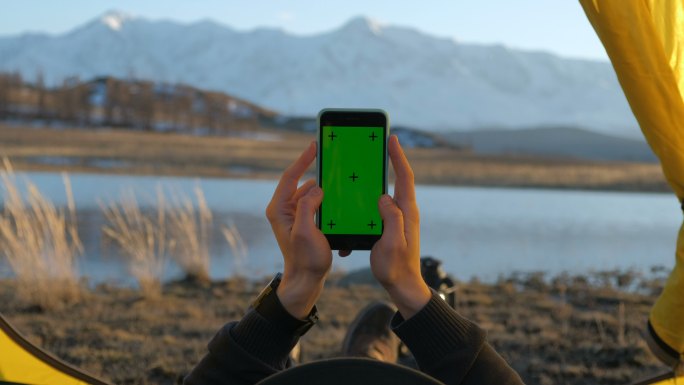 一个男人正在使用绿色屏幕的手机