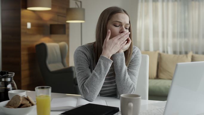 打呵欠的女人用笔记本电脑