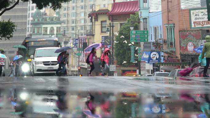 带着雨伞的小学生正穿过一条繁忙的城市街道