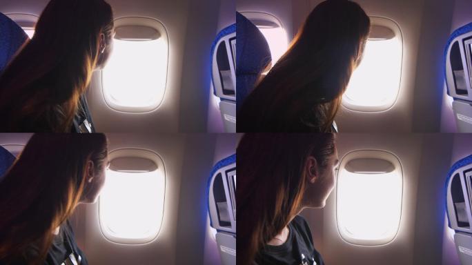 美丽的女孩从飞机的窗户向外看