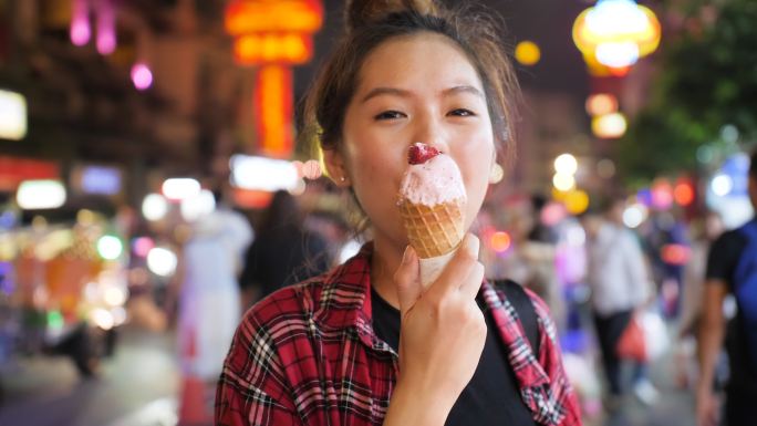 年轻女人在夜市享用草莓冰淇淋