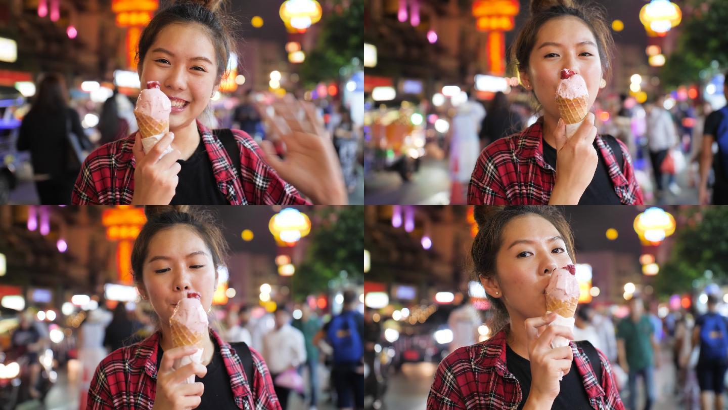 年轻女人在夜市享用草莓冰淇淋