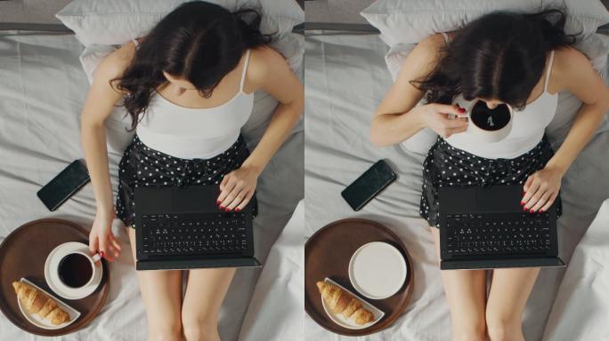 女孩坐在床上用笔记本电脑，并吃面包喝咖啡