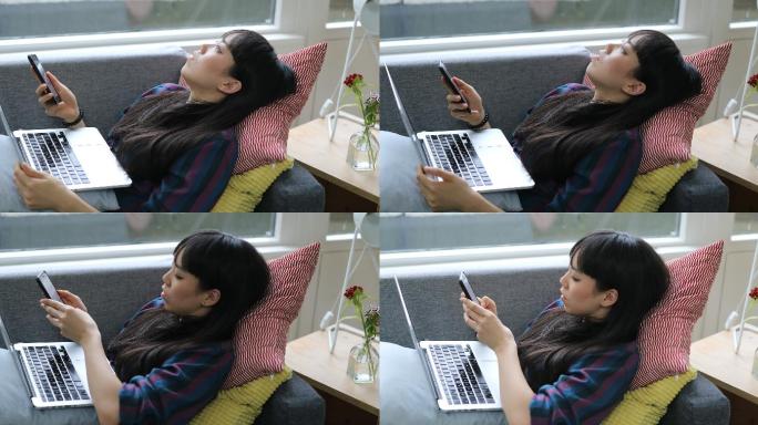 躺在沙发上使用智能手机的女人