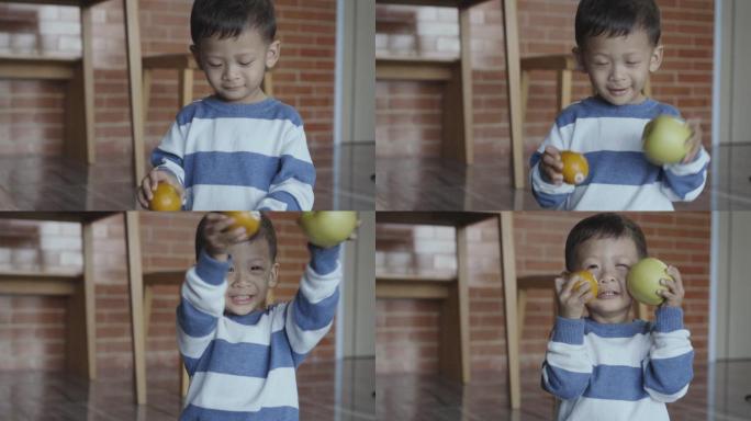 小男孩抱着橘子和苹果，家庭和童年的概念