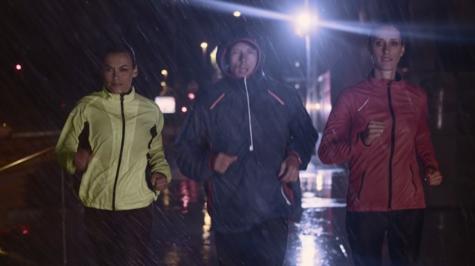 一名男子和两名女子在大雨中跑步