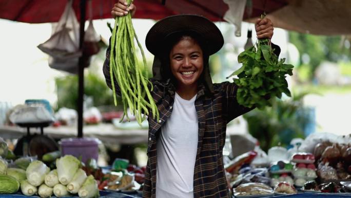 年轻女人在摊子前拿着蔬菜