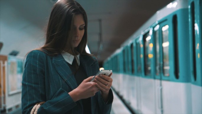 等待地铁时使用智能手机的女人