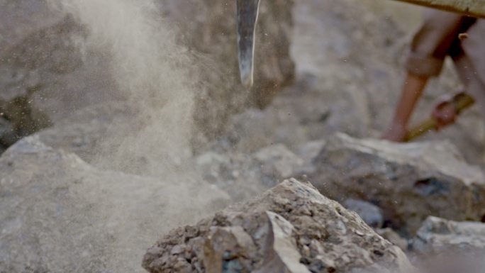 矿工或掘金者用挖斧打碎岩石