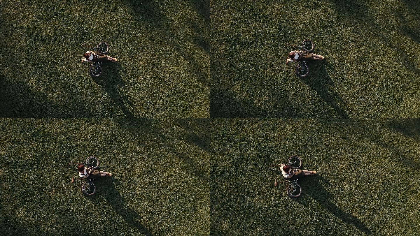 女自行车手坐在草坪上正在使用手机