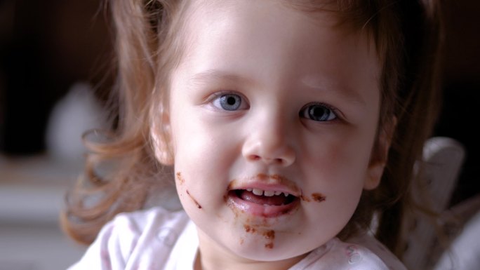 可爱的小女孩正在吃巧克力，对着镜头眨眼