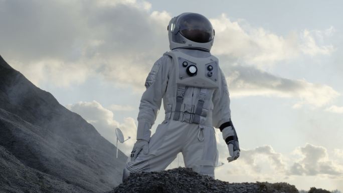 宇航员站在冰冻的外星行星的山上环顾四周。