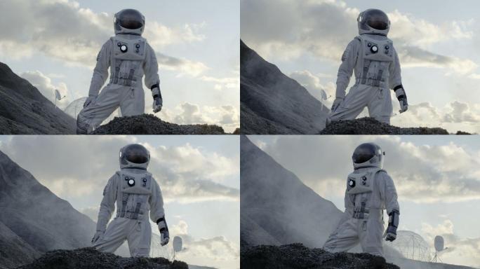 宇航员站在冰冻的外星行星的山上环顾四周。