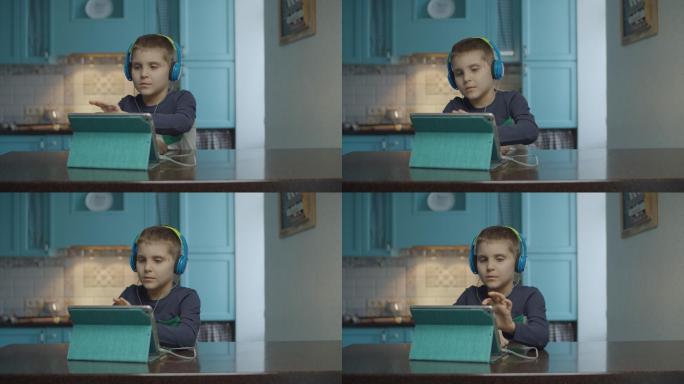自闭症男孩在厨房用带耳机的平板电脑