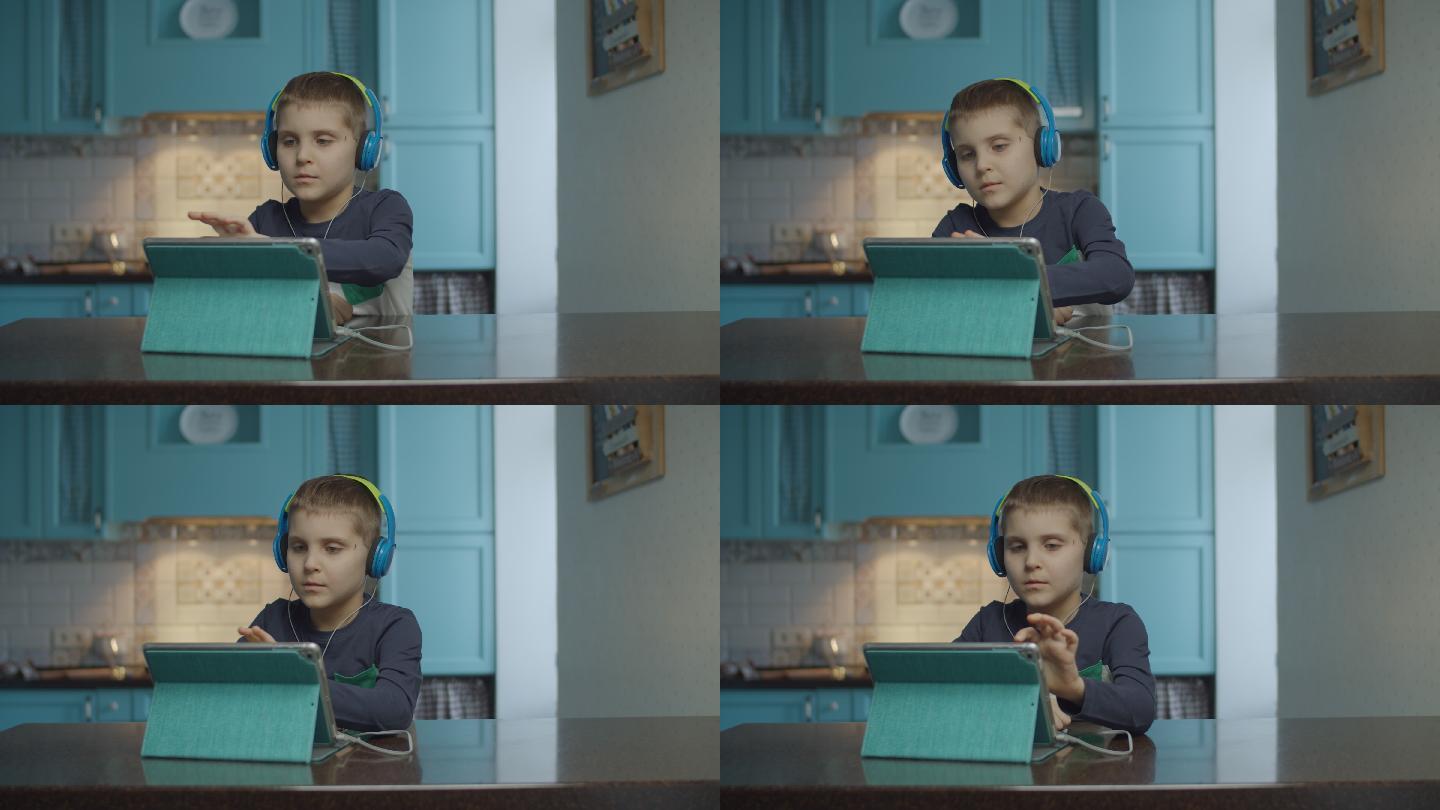 自闭症男孩在厨房用带耳机的平板电脑