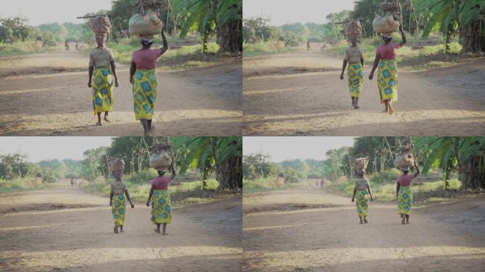 两个女人走在非洲村庄的土路上