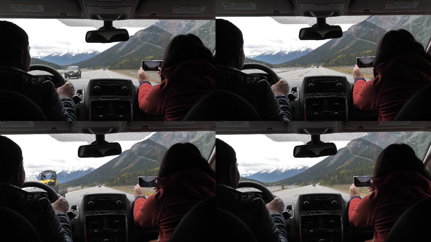 一对情侣在冬天开车用手机在乡村公路上拍照