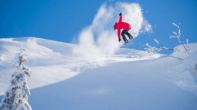 在阳光明媚的冬日表演特技的滑雪运动员
