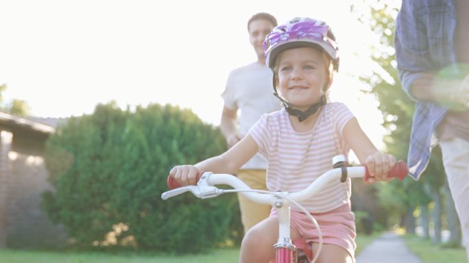 小女孩在家人的帮助下学骑自行车