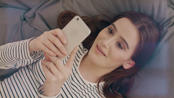 在视频通话的女子实拍开心躺在床上视频聊天