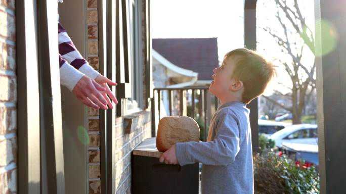 可爱的小孩把自制面包带到邻居家门口