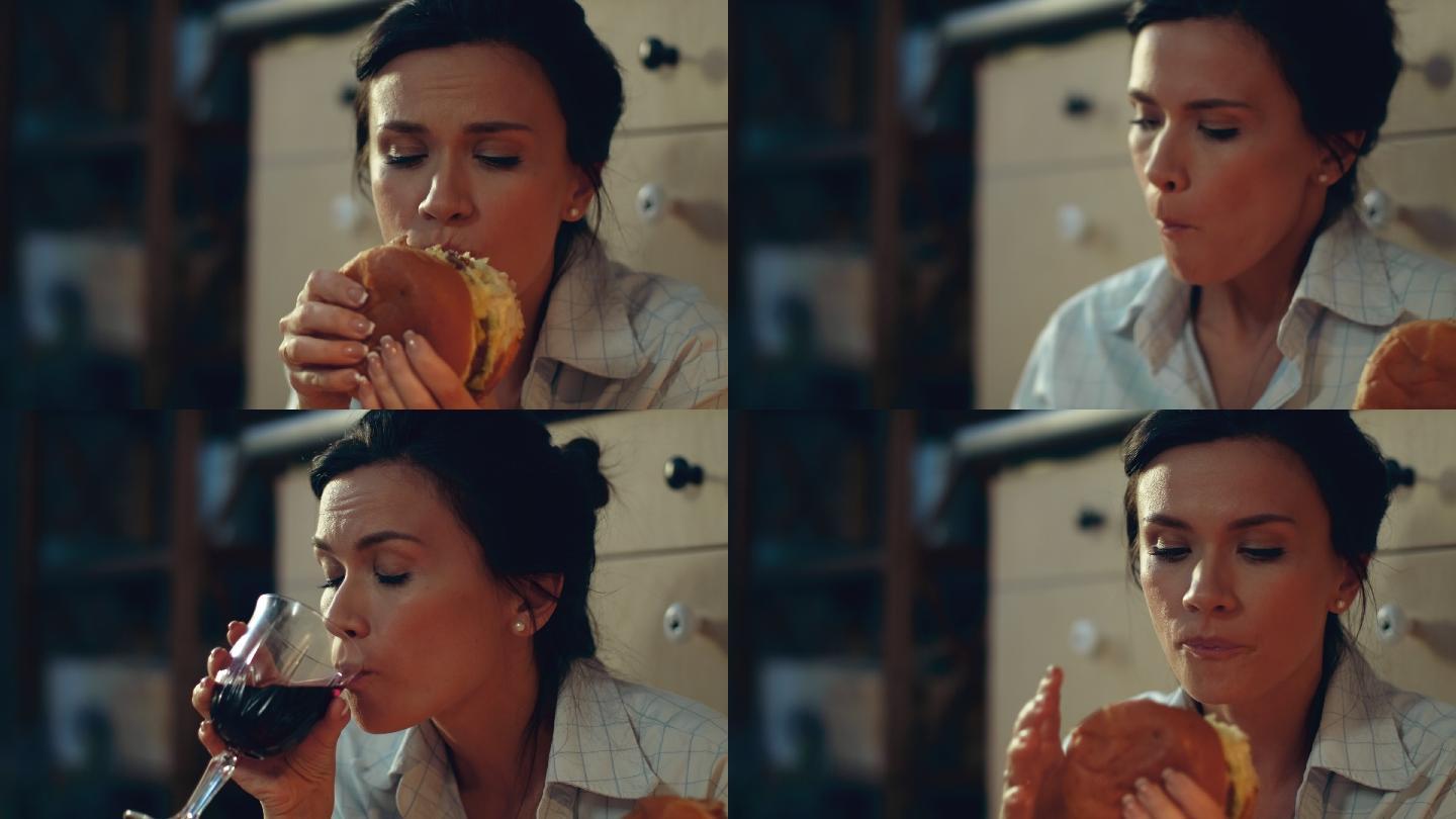 饥饿的女孩在地板上吃汉堡。