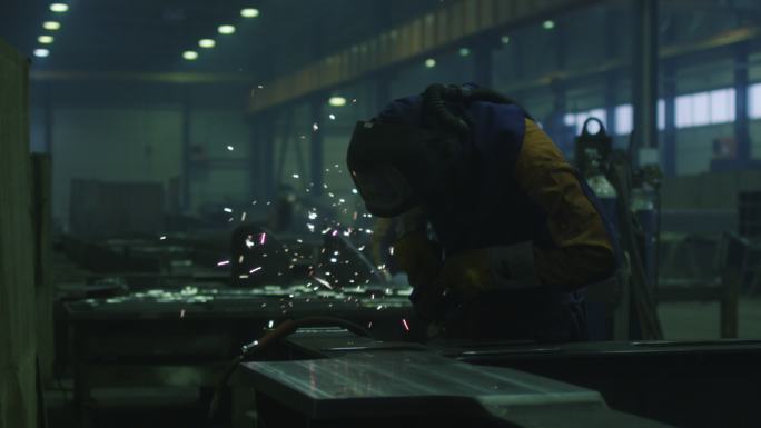 一家工厂的重工业工人正在角磨机上加工金属