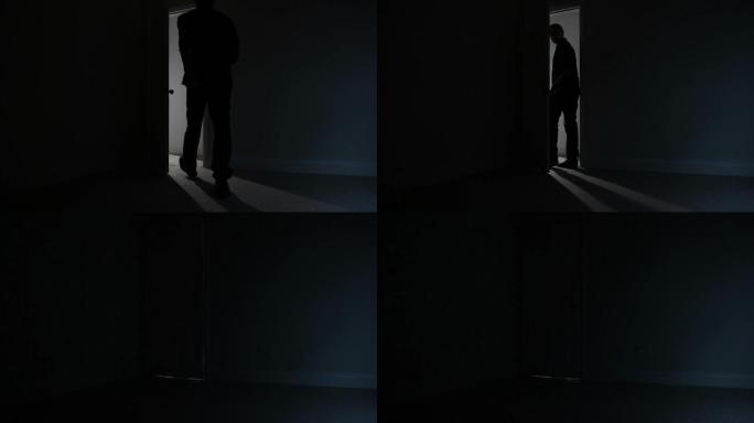男人离开黑暗房间的剪影。