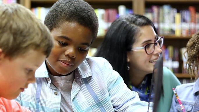 小学辅导员与学生在图书馆学习