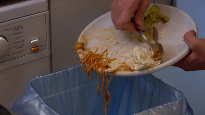 把意大利面剩饭倒进垃圾箱。