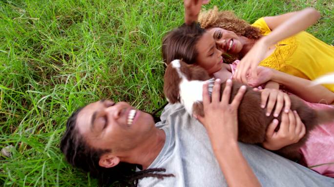 一家人带着他们的狗躺在草坪上