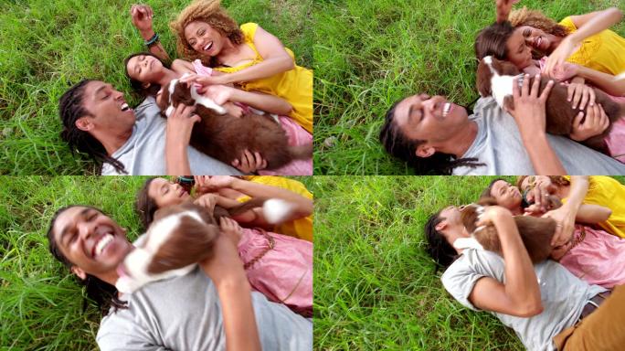 一家人带着他们的狗躺在草坪上