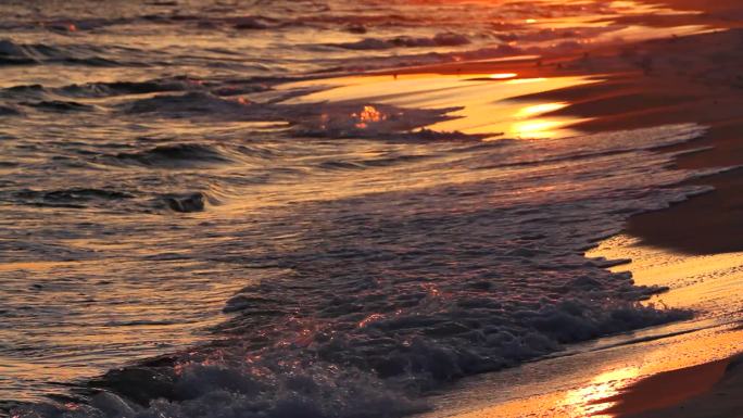日落时海浪在沙滩上卷起