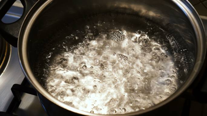 炉子上锅里的水沸腾的特写镜头。