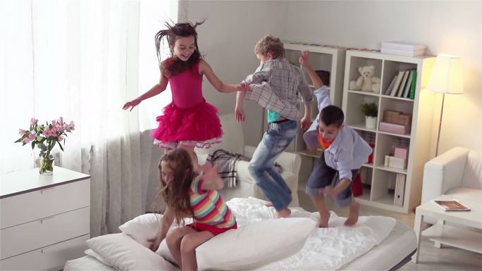 四个精力充沛孩子一起在床上蹦蹦跳跳
