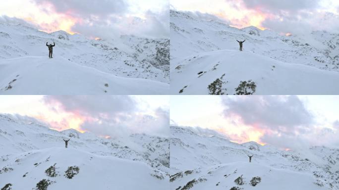 冬季空中登山运动员在山顶上胜利地举起双手