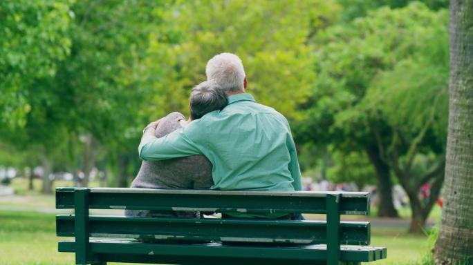 一对老年夫妇坐在公园长凳上的镜头