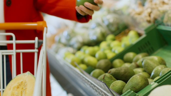 在超级市场：妇女从新鲜农产品区挑选水果