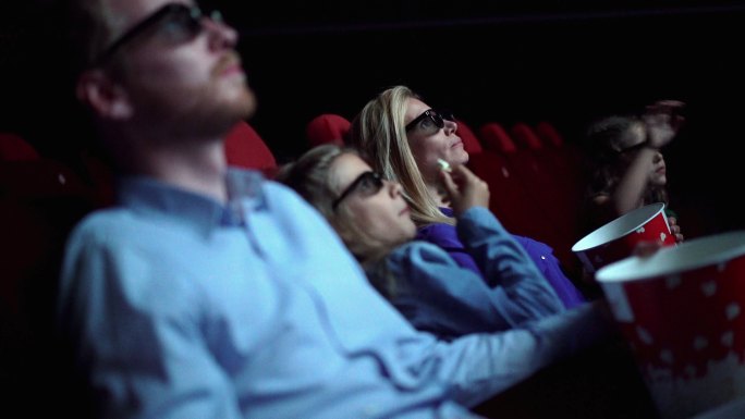 电影院里的家人们一边看电影一边吃爆米花