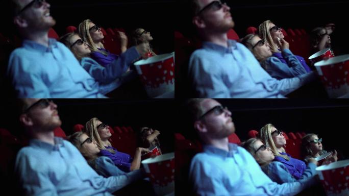 电影院里的家人们一边看电影一边吃爆米花