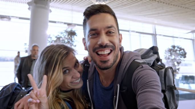 年轻夫妇在机场门口等待登机时自拍