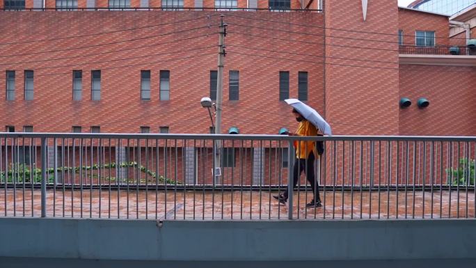 红砖墙打伞人路过城市人文