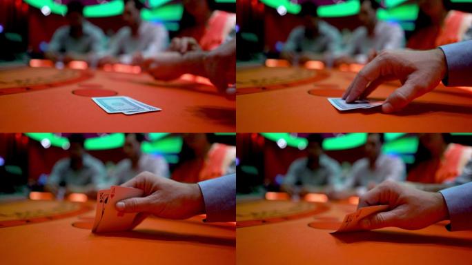 在牌桌上赌博的一个男人举起他的牌来看