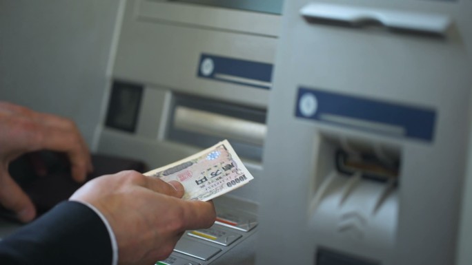 男子数着从ATM机里取出的日元
