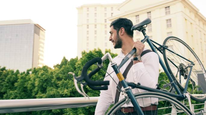 一个英俊的年轻商人在城里扛着自行车行走