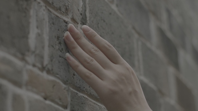 实拍美女手指抚过砖墙