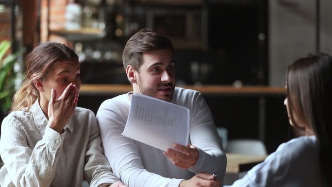 恼怒的年轻夫妇拿着文件和经理争吵