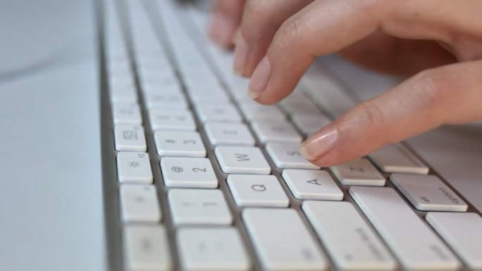 一个女人用白色键盘打字的特写镜头