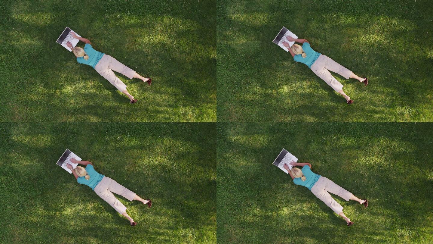 躺在草地上用笔记本电脑的女人