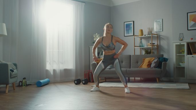运动健身女孩在客厅里做有氧运动